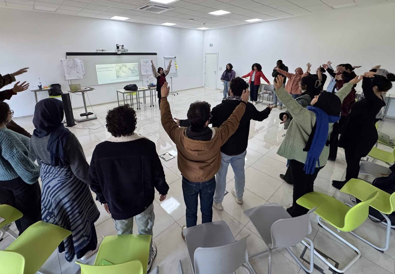Collective grounding exercise University students engaging in a collective grounding exercise during a TEP workshop, using embodied movement to build trust, emotional regulation, and group cohesion prior to dialogical work on sensitive issues.