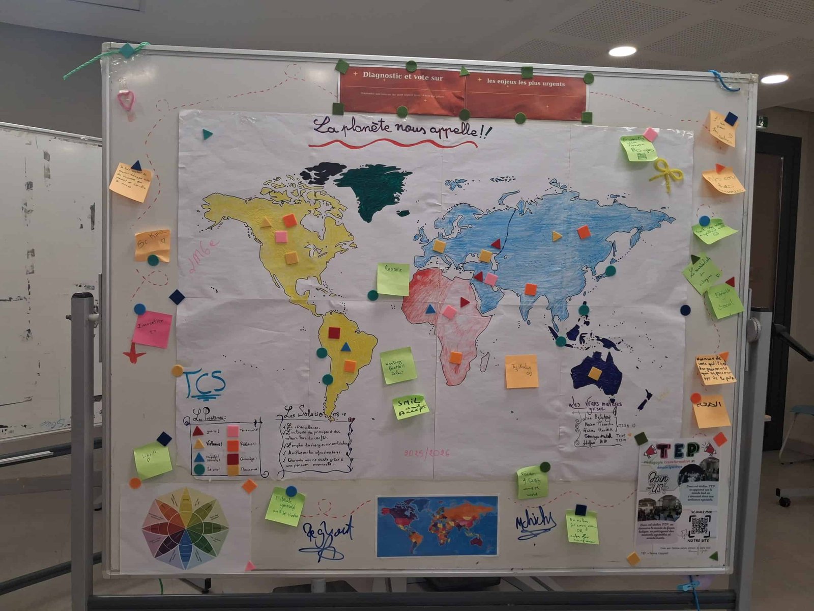 tep-student-world-map-la-planete-nous-appelle-lycee-morocco-2026 Student-created world map titled 'La planète nous appelle!' (The planet is calling us!), with colour-coded sticky notes and markers identifying global problems and solutions across continents, created during a Transformative-Emancipatory Pedagogy (TEP) session at Lycée Mohammed VI d'Excellence, Morocco, 2026.