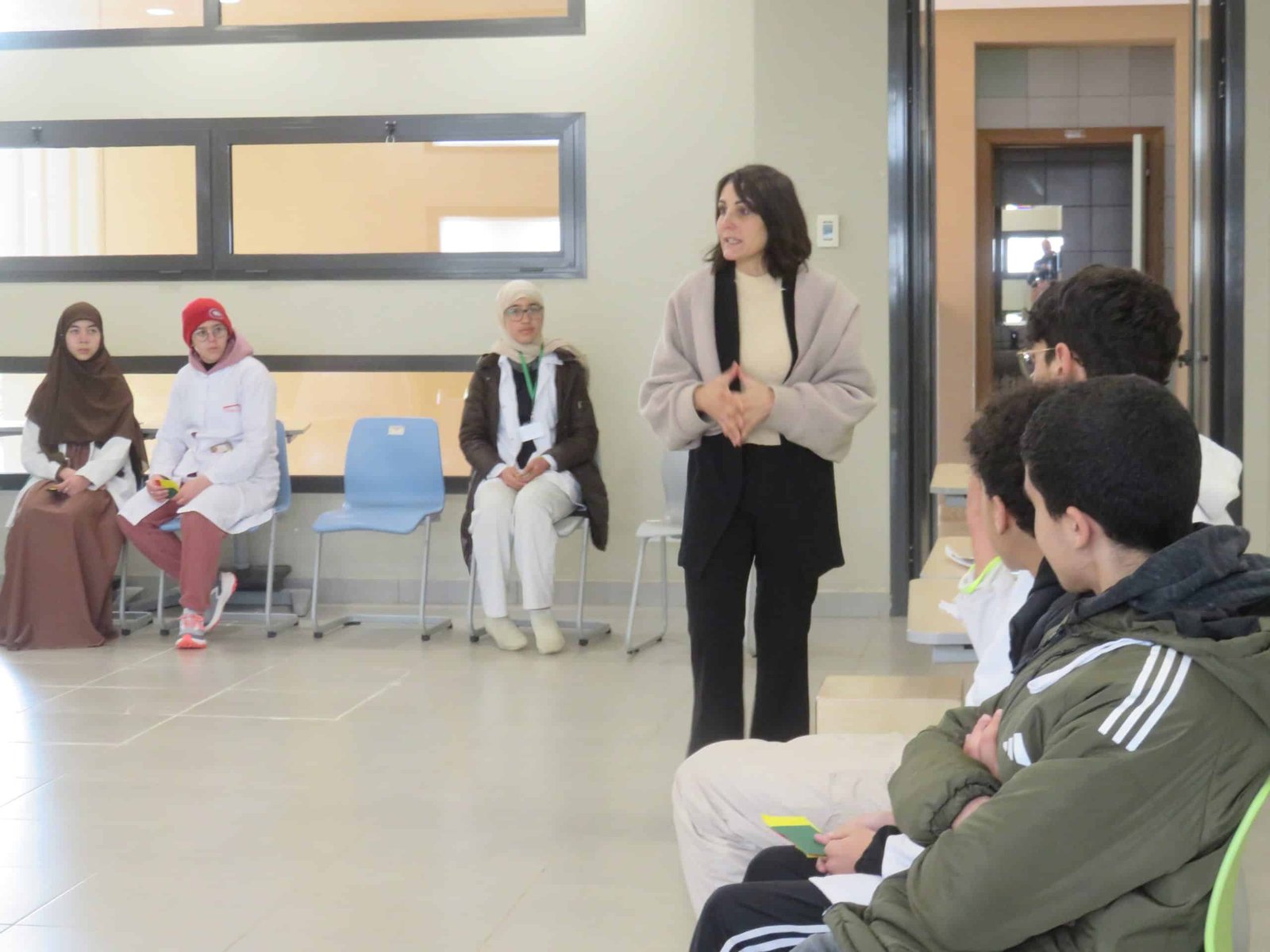 tep-teresa-cappiali-facilitating-circle-session-lycee-morocco-2026 Dr. Teresa M. Cappiali facilitating a Transformative-Emancipatory Pedagogy (TEP) circle session at Lycée Mohammed VI d'Excellence, Morocco 2026, with students seated and listening attentively on both sides.