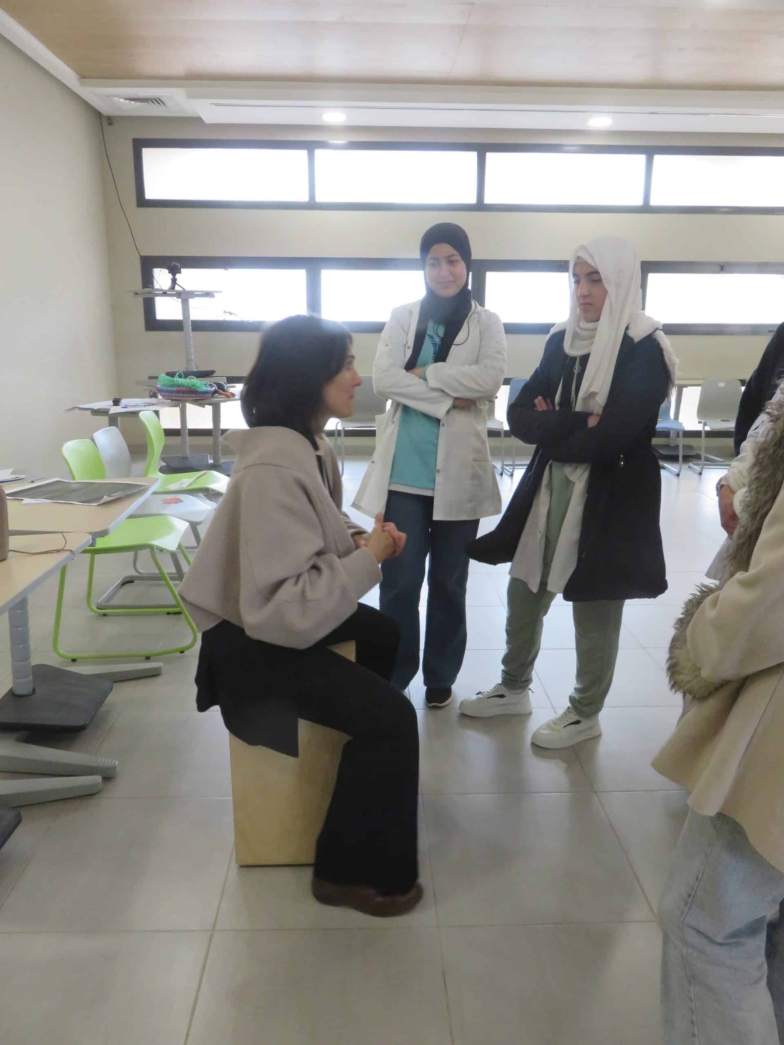 tep-workshop-facilitator-student-dialogue-morocco Facilitator seated and engaged in close dialogue with two students standing during a reflective exchange in a Transformative-Emancipatory Pedagogy (TEP) workshop in Morocco, March 2026.
